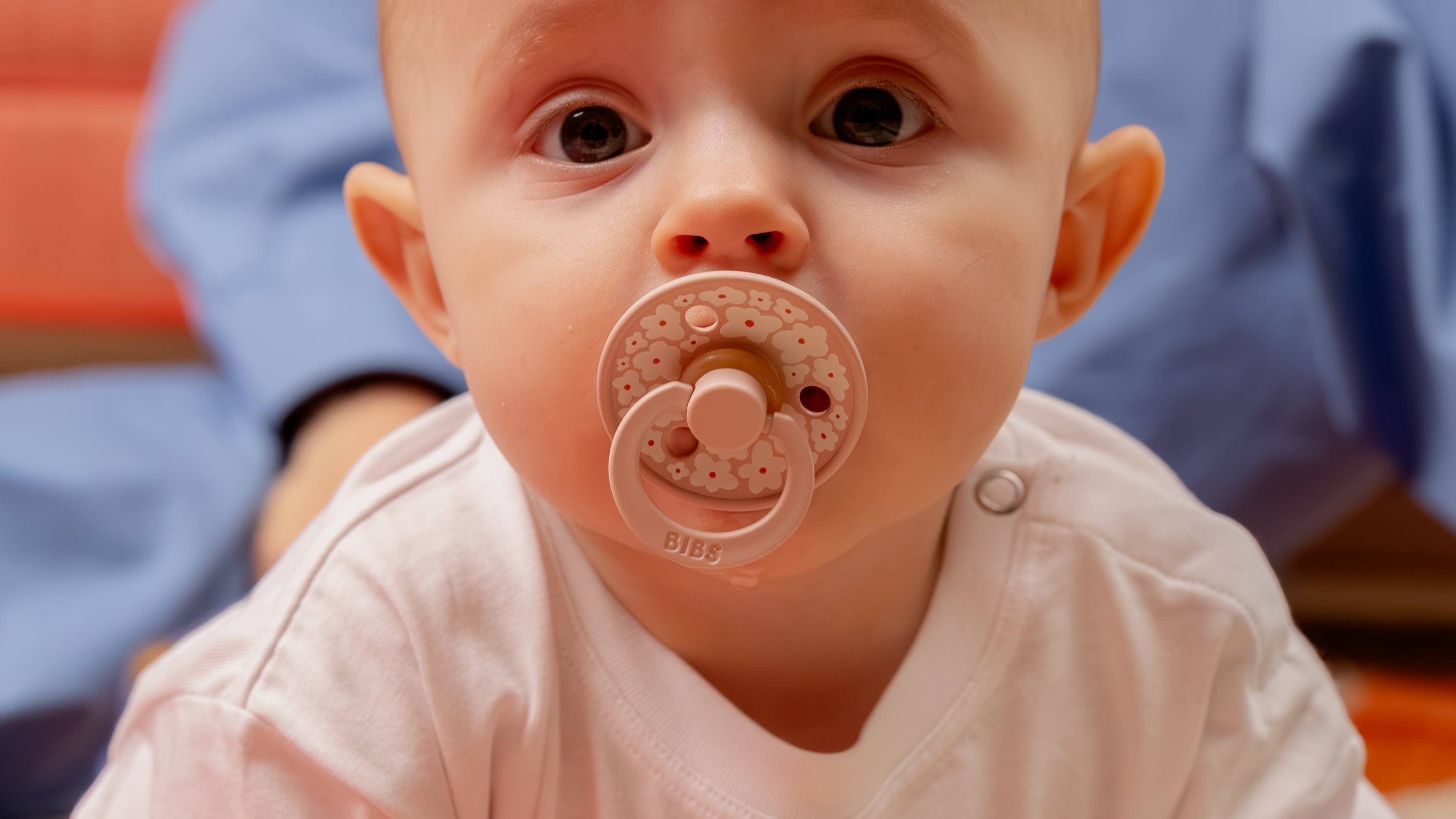 Sfeerfoto van baby met bibs speen in mond