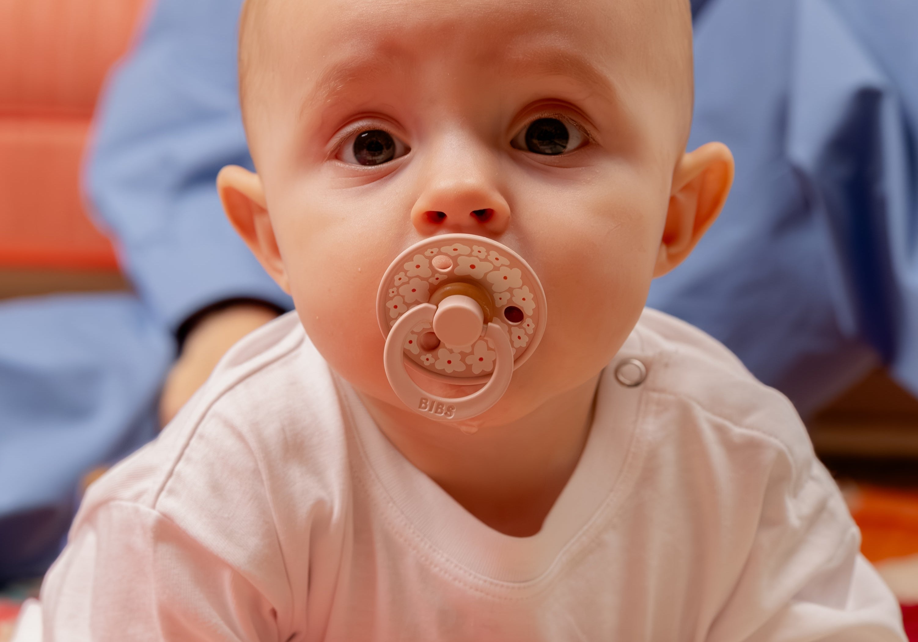 Sfeerfoto van baby met bibs speen in mond