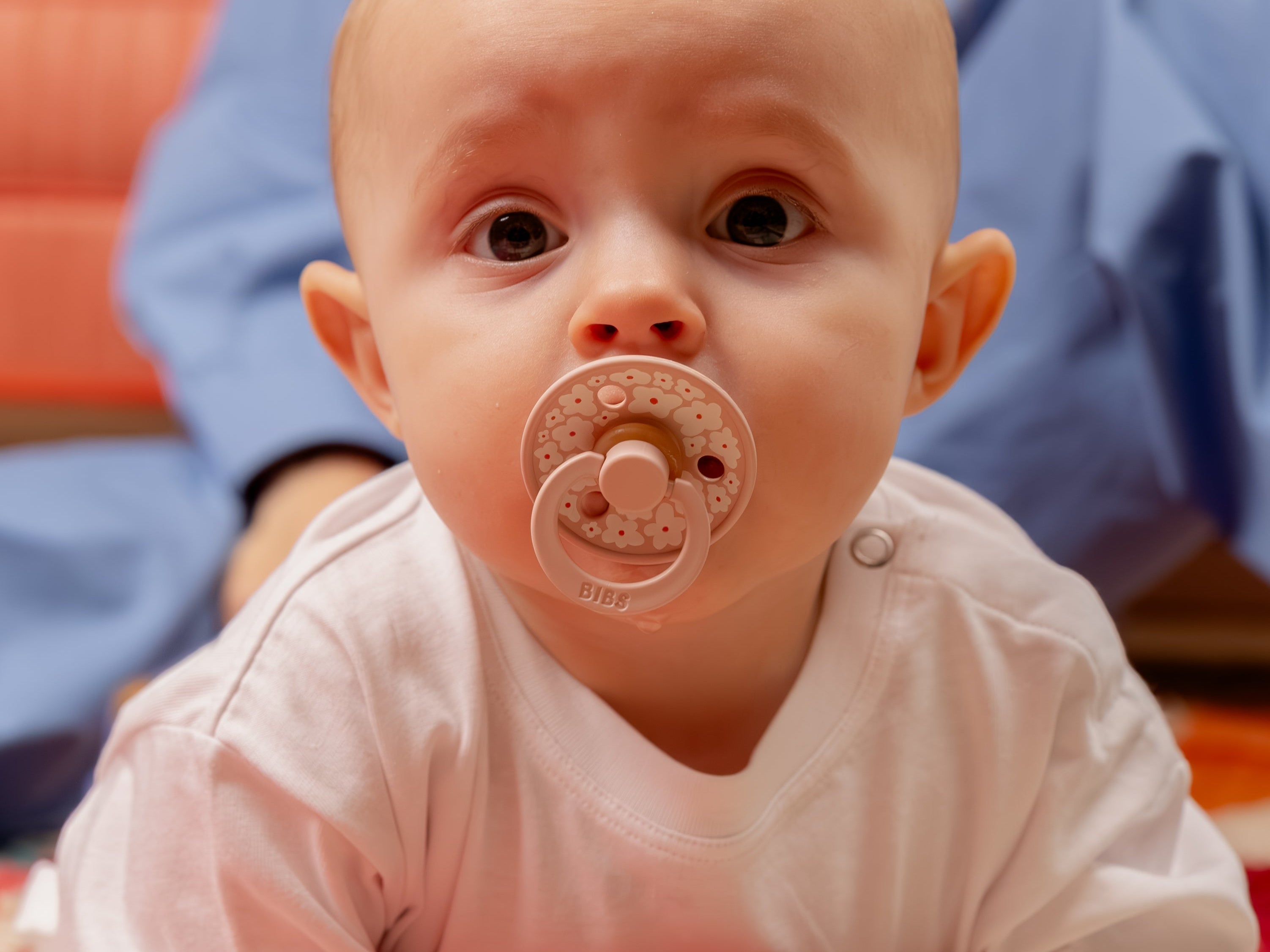 Sfeerfoto van baby met bibs speen in mond