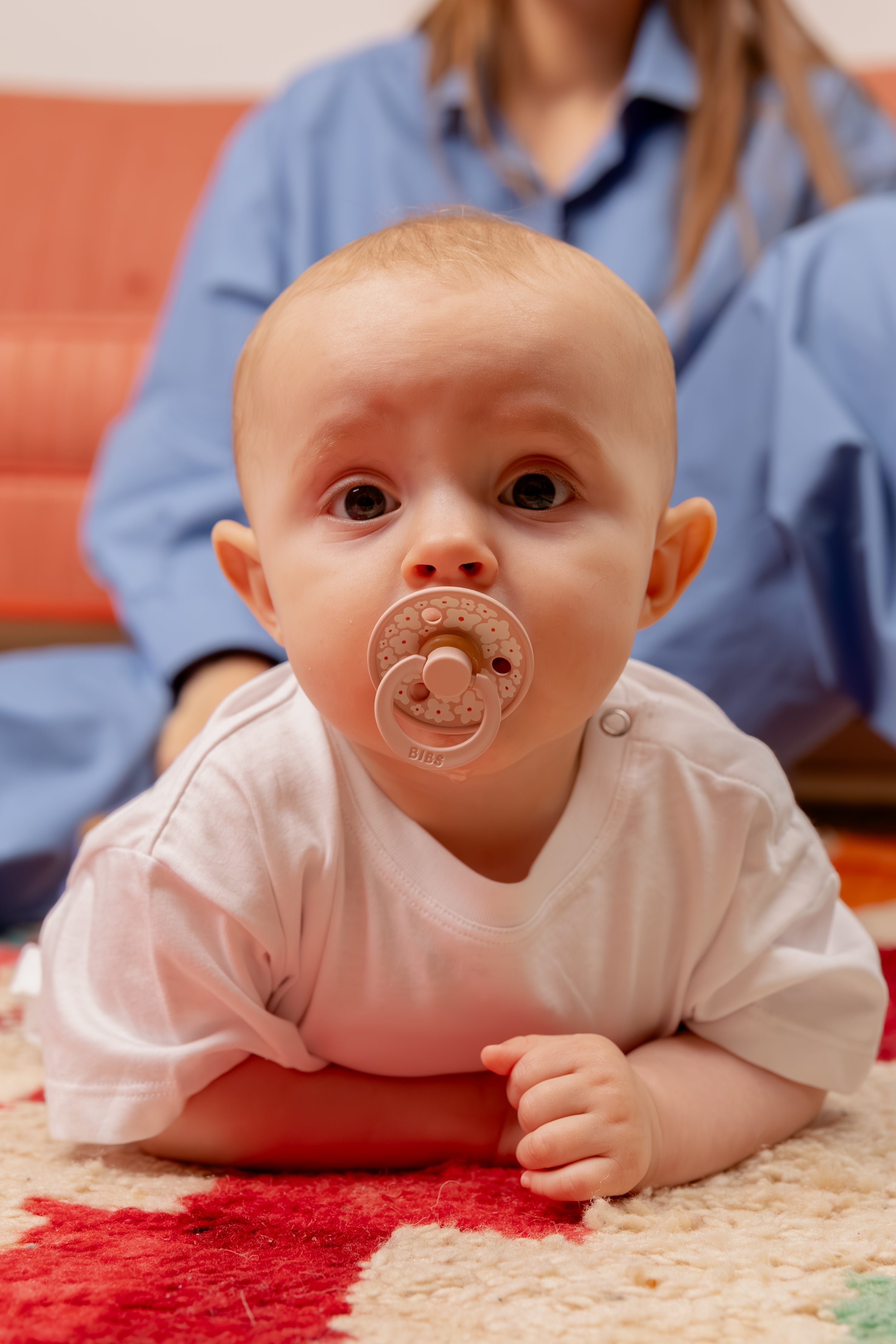Sfeerfoto van baby met bibs speen in mond