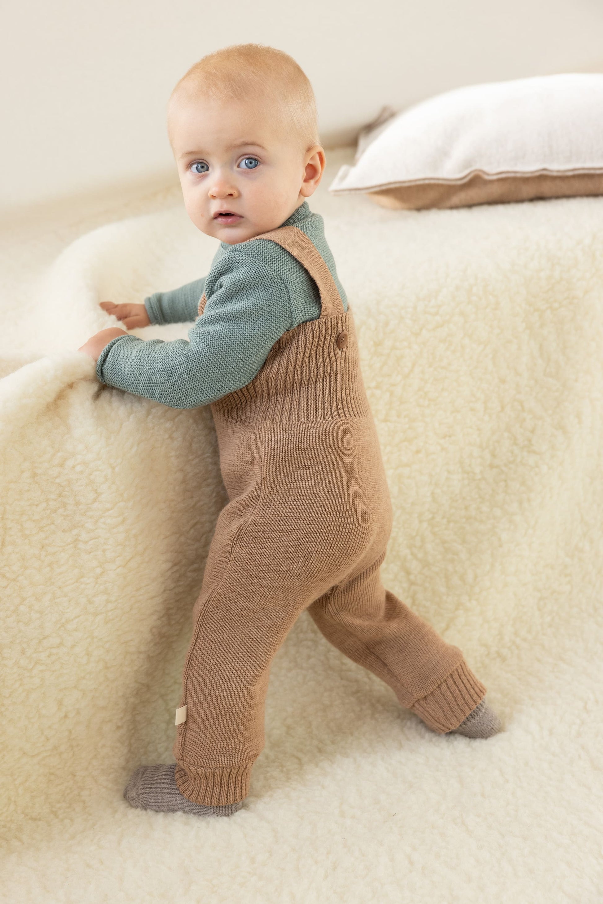 Baby draagt Disana wollen tuinbroek tijdens eerste stapje