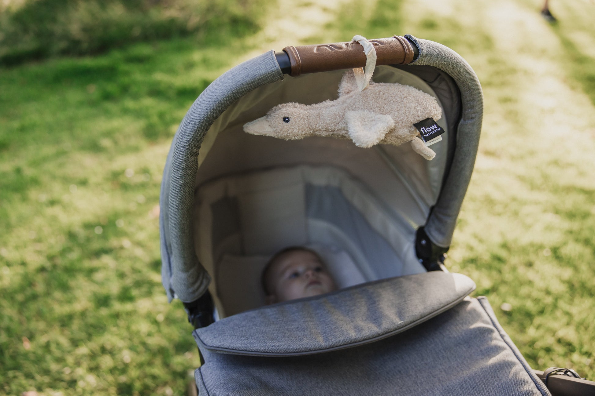 Compacte ruisknuffel van Flow bevestigd aan kinderwagenwieg – perfect als slaaphulp voor baby’s onderweg