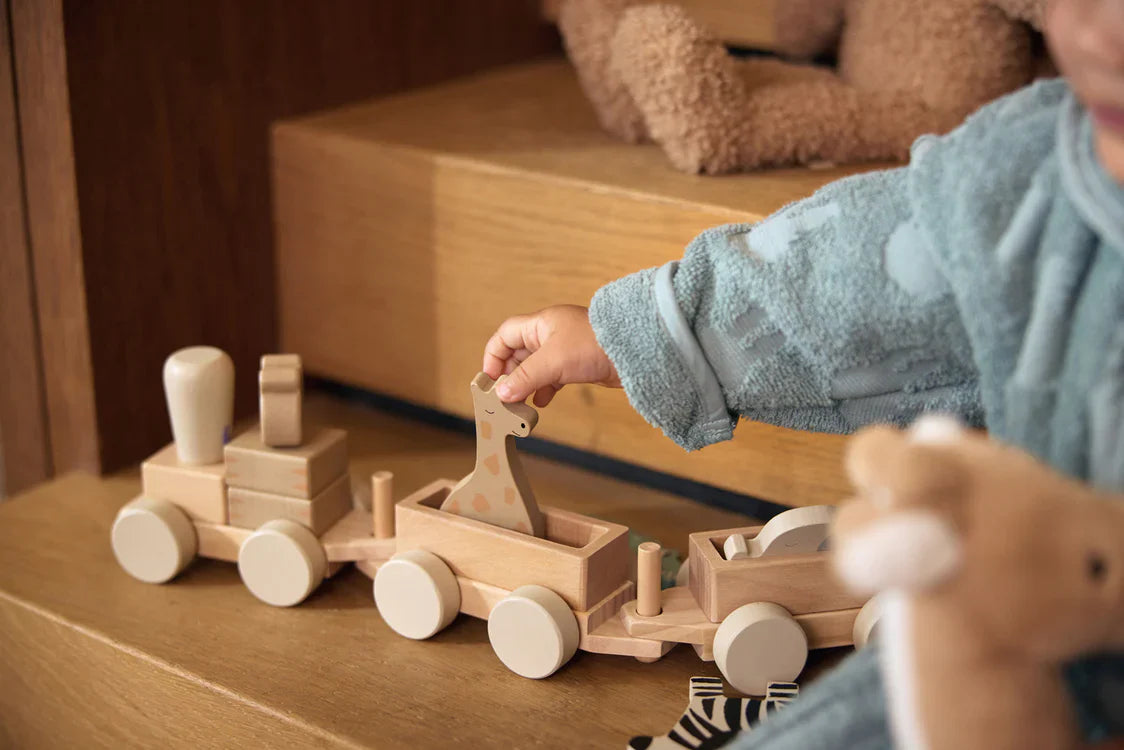 Kindje speelt met houten dieren en speelgoedtrein