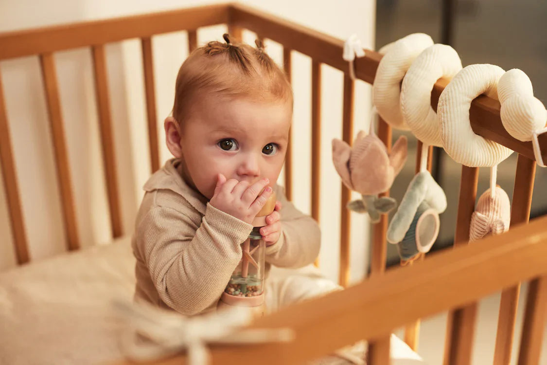 Sfeerfoto van baby die met regenrammelaar speelt