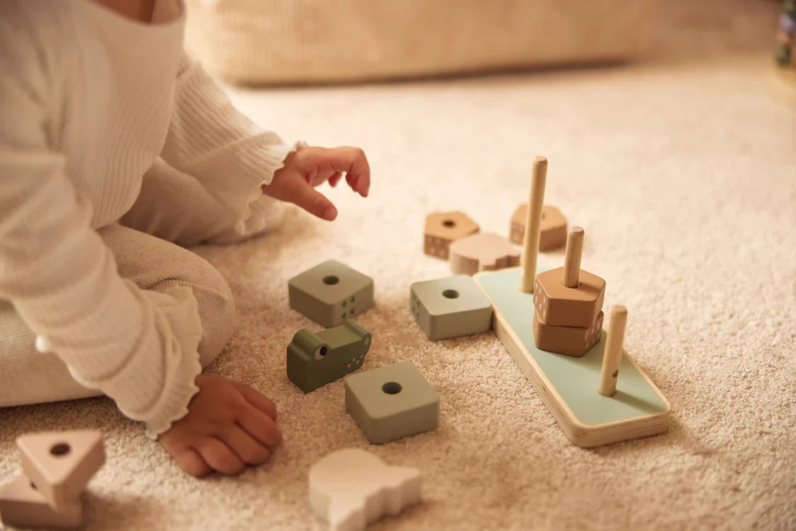 Sfeerfoto van kindje die met houten stapeldieren speelt
