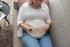 Vrouw legt Lexie Heating Pillow op buik voor natuurlijke verlichting van menstruatieklachten