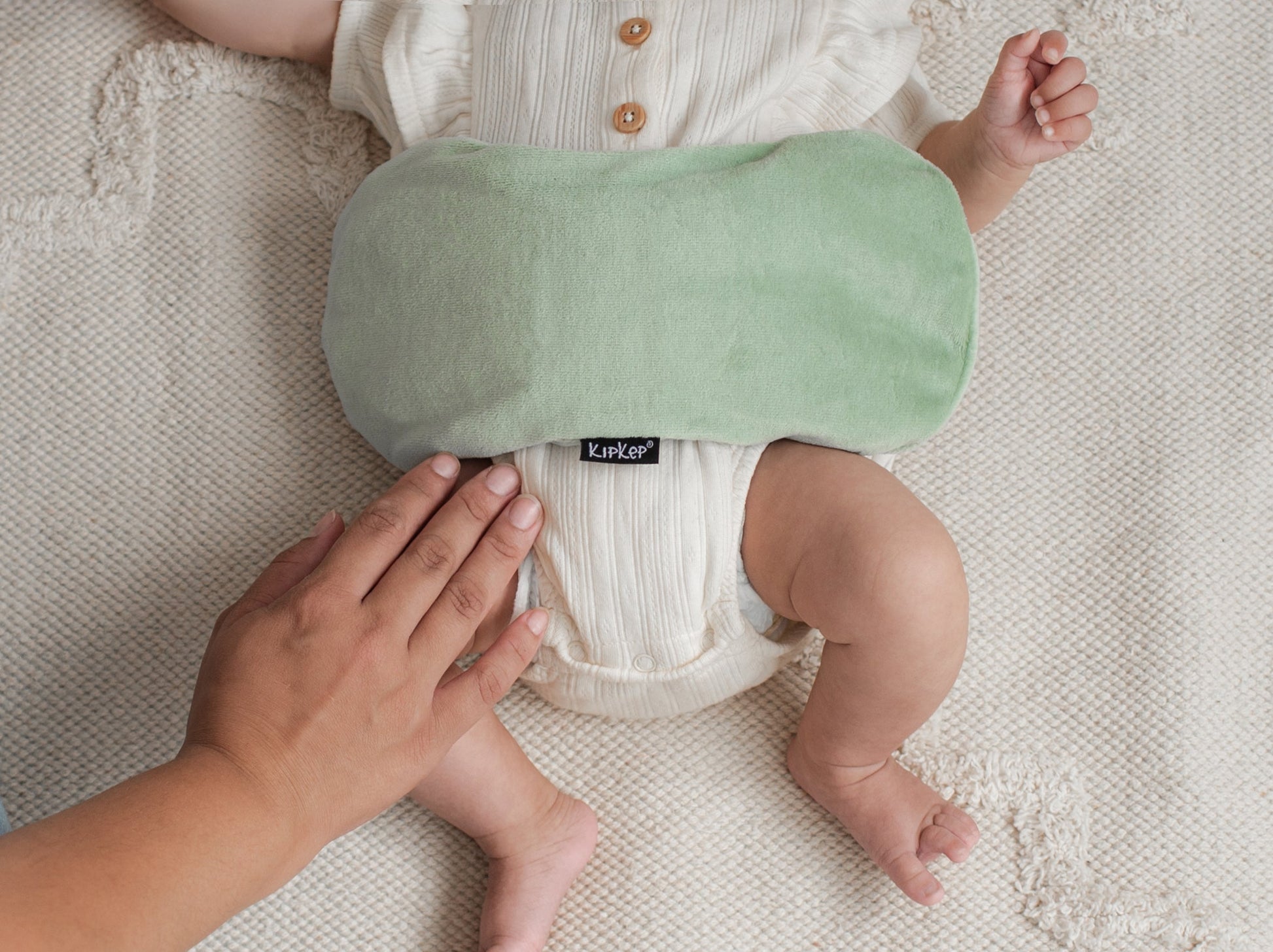 Ouder legt het KipKep Woller warmtekussen comfortabel op de buik van de baby voor extra warmte