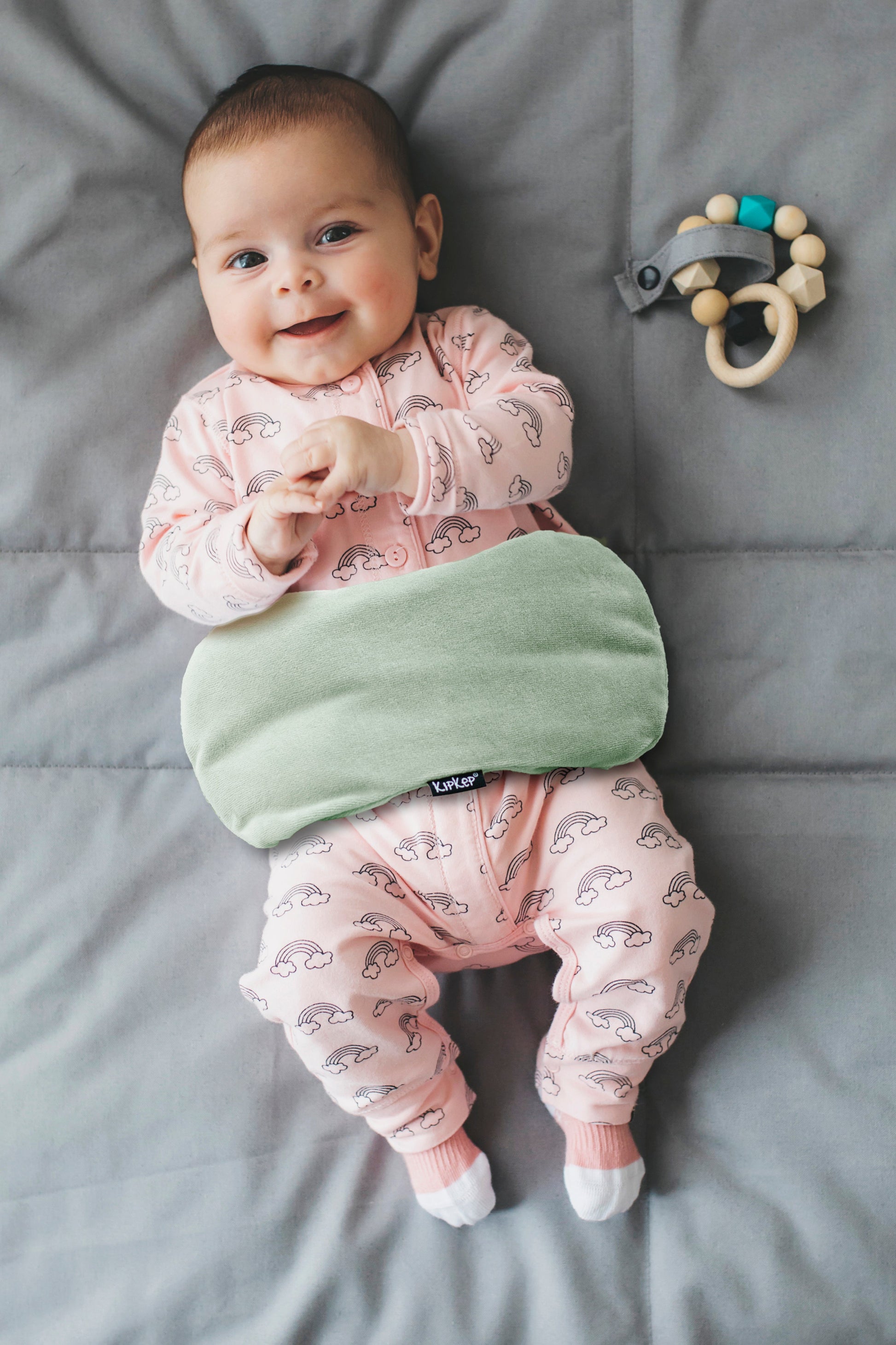 Baby ontspannend met het KipKep Woller warmtekussen in Pale Green op schoot