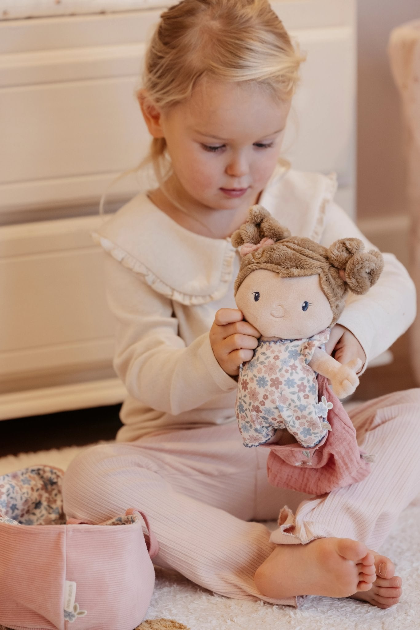 Kind verzorgt babypop Rosa en speelt met aankleden, knuffelen en verzorgen