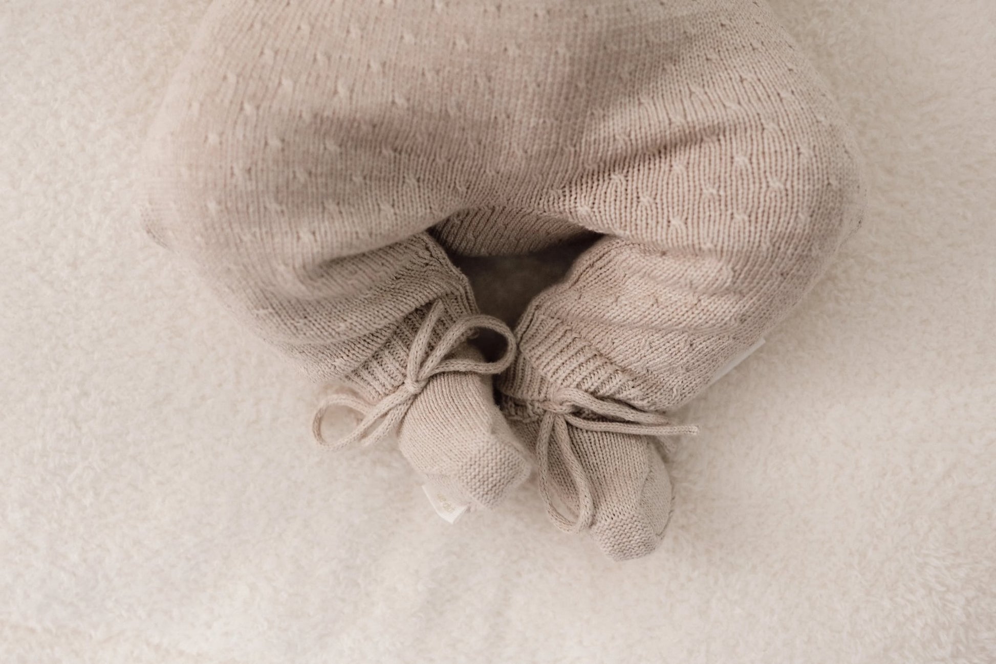 Beige gebreide babyslofjes met strikjes voor kleine voetjes