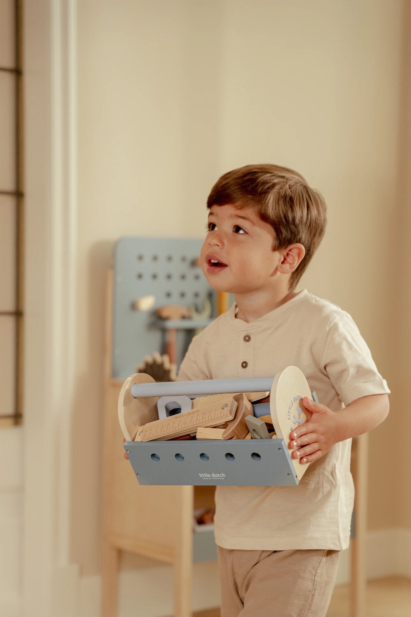 Jongen draagt de Little Dutch gereedschapskist als duurzaam kindercadeau voor kleine bouwers