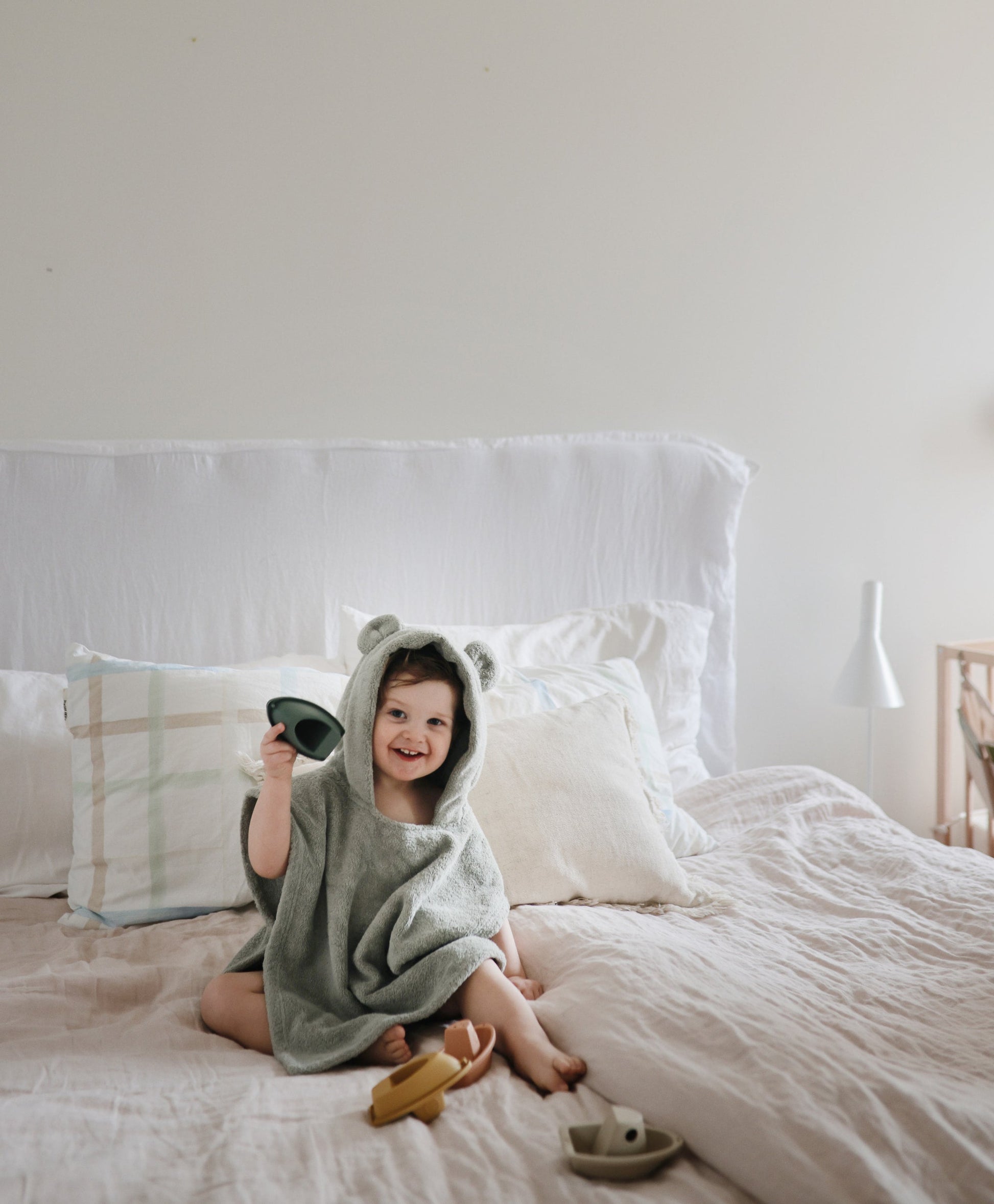 kindje speelt op bed met mushie badbootjes