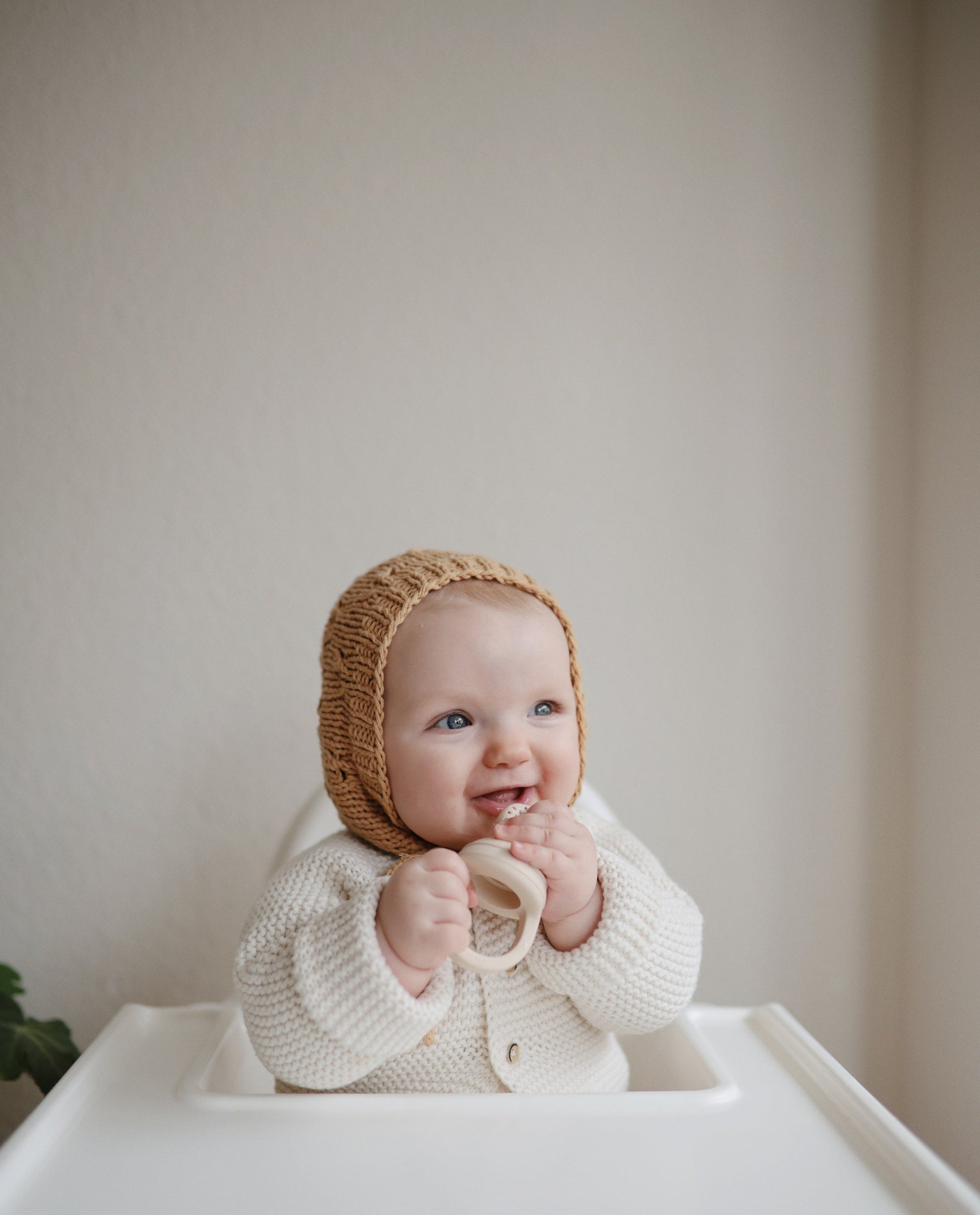 baby bijt op mushie fruitspeen in kinderstoel