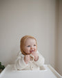 baby bijt op mushie fruitspeen in kinderstoel