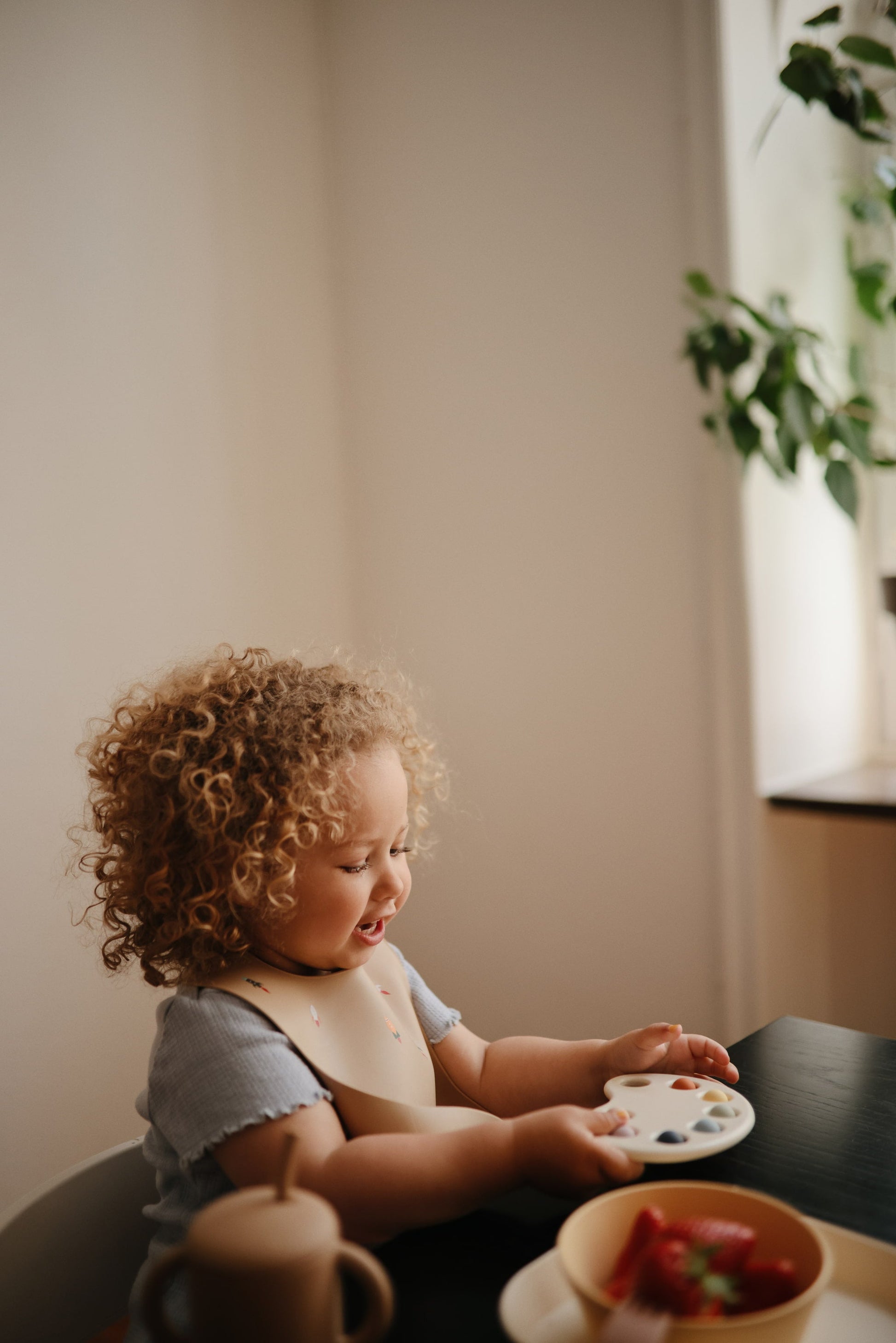 kind met siliconen mushie slab aan tafel