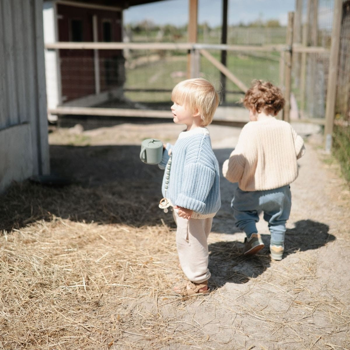 twee kinderen die buitenspelen met mushie snackbeker 