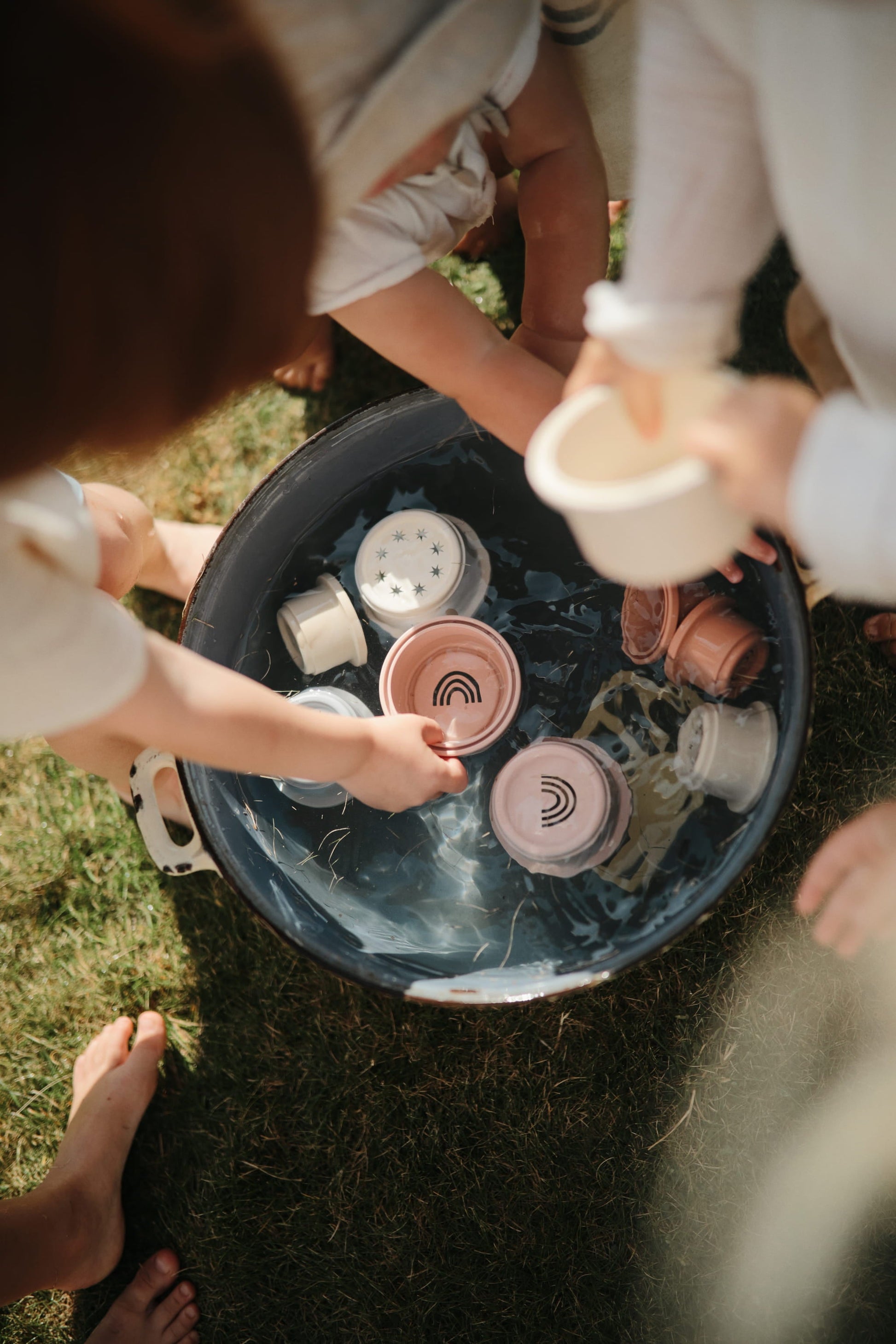 kinderen die spelen met mushie stapelbekers in water