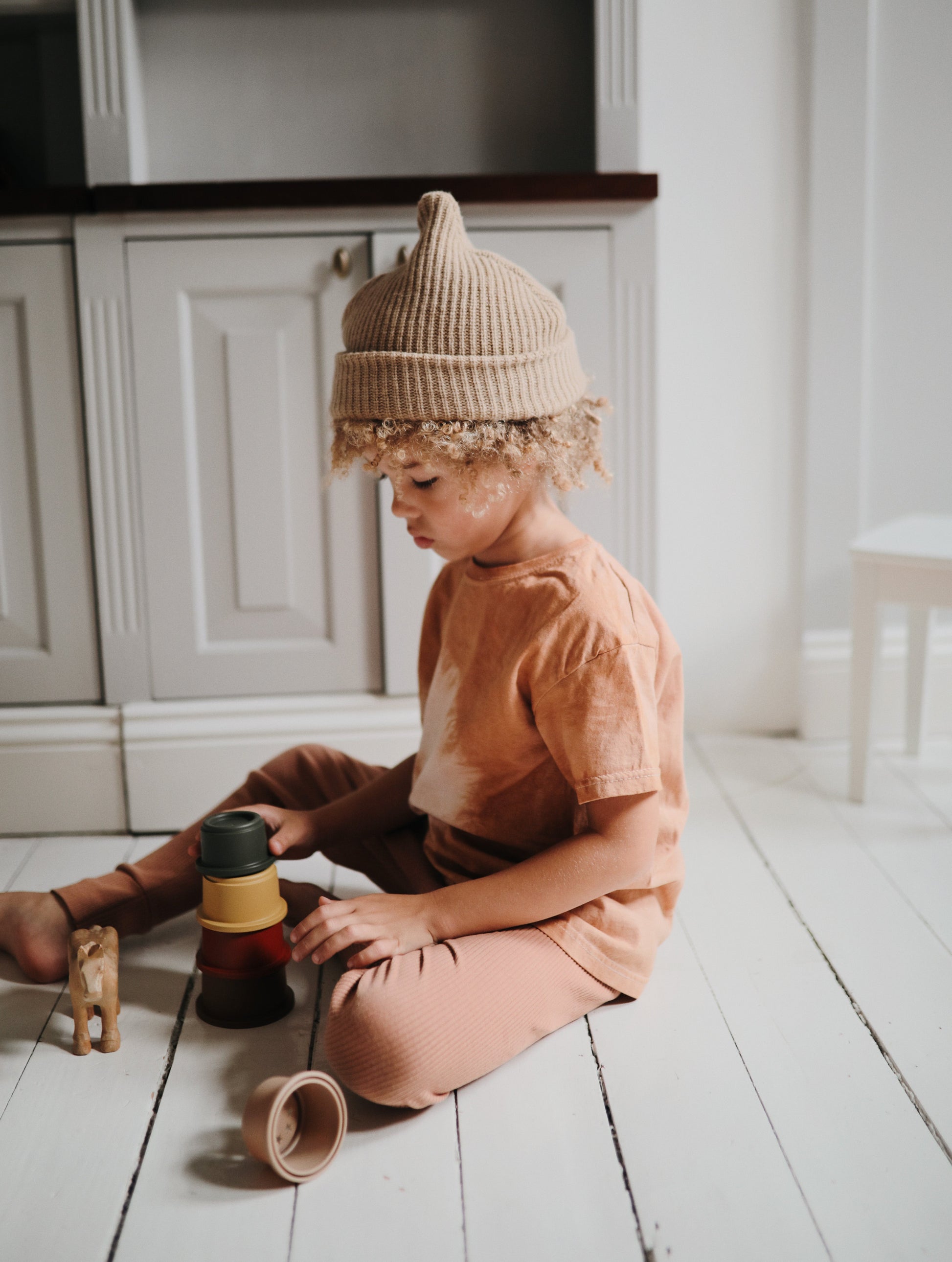 mushie stackingcups in retrokleuren met spelend kind