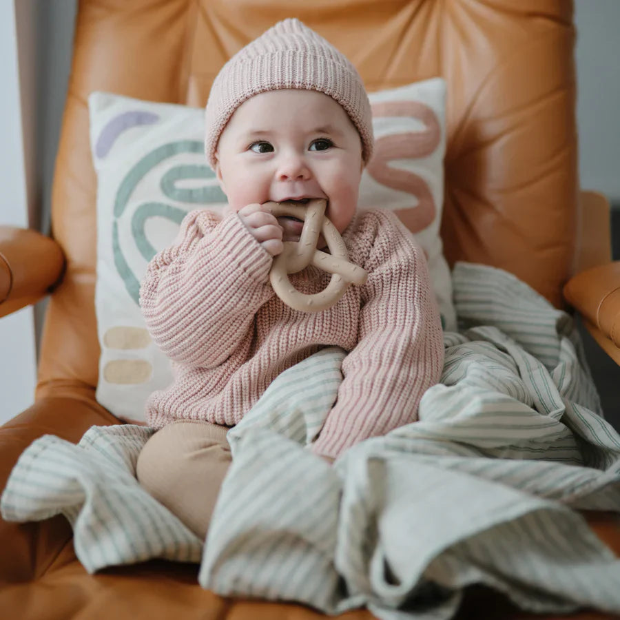Sfeerfoto van baby die op pretzel bijtring bijt van mushie