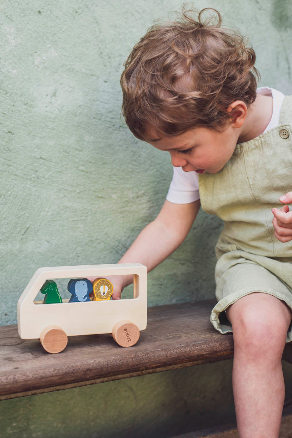 kind speelt met houten dieren bus van trixie 