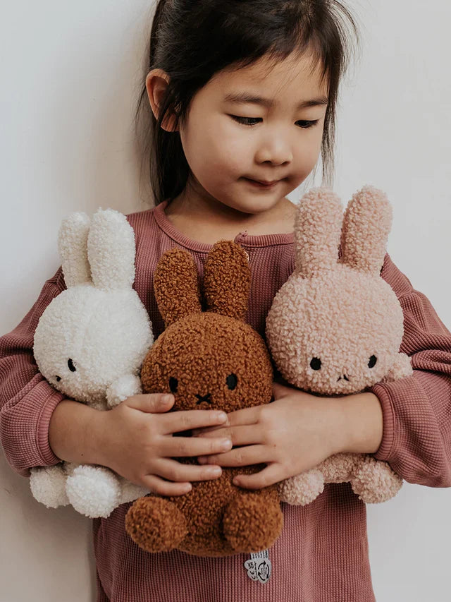 meisje knuffelt met diverse kleuren nijntjes 